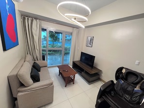 Una sala de estar con un sofá, una mesa de centro, un televisor y un sillón de masaje.