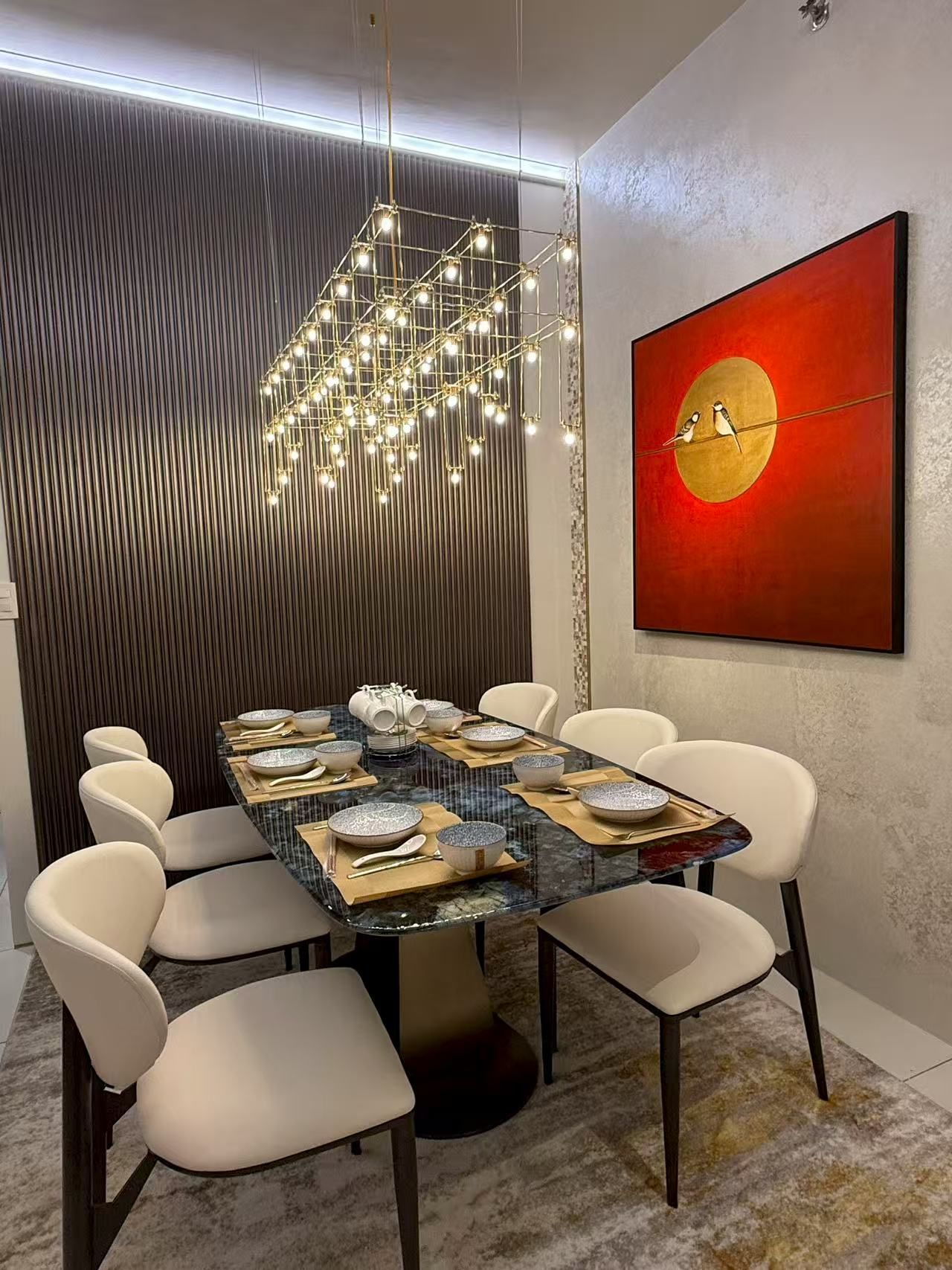 Een moderne eetruimte met een tafel met glazen blad, witte stoelen en een hanglamp.