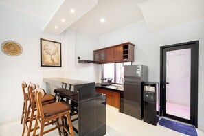 A modern kitchen with a dining area, wooden cabinets, a refrigerator, and a water dispenser.