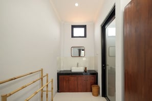 A bathroom with a wooden cabinet, a white sink, and a mirror above it.