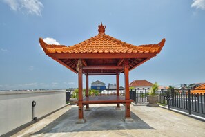 A traditional pavilion with a tiled roof on a rooftop terrace.