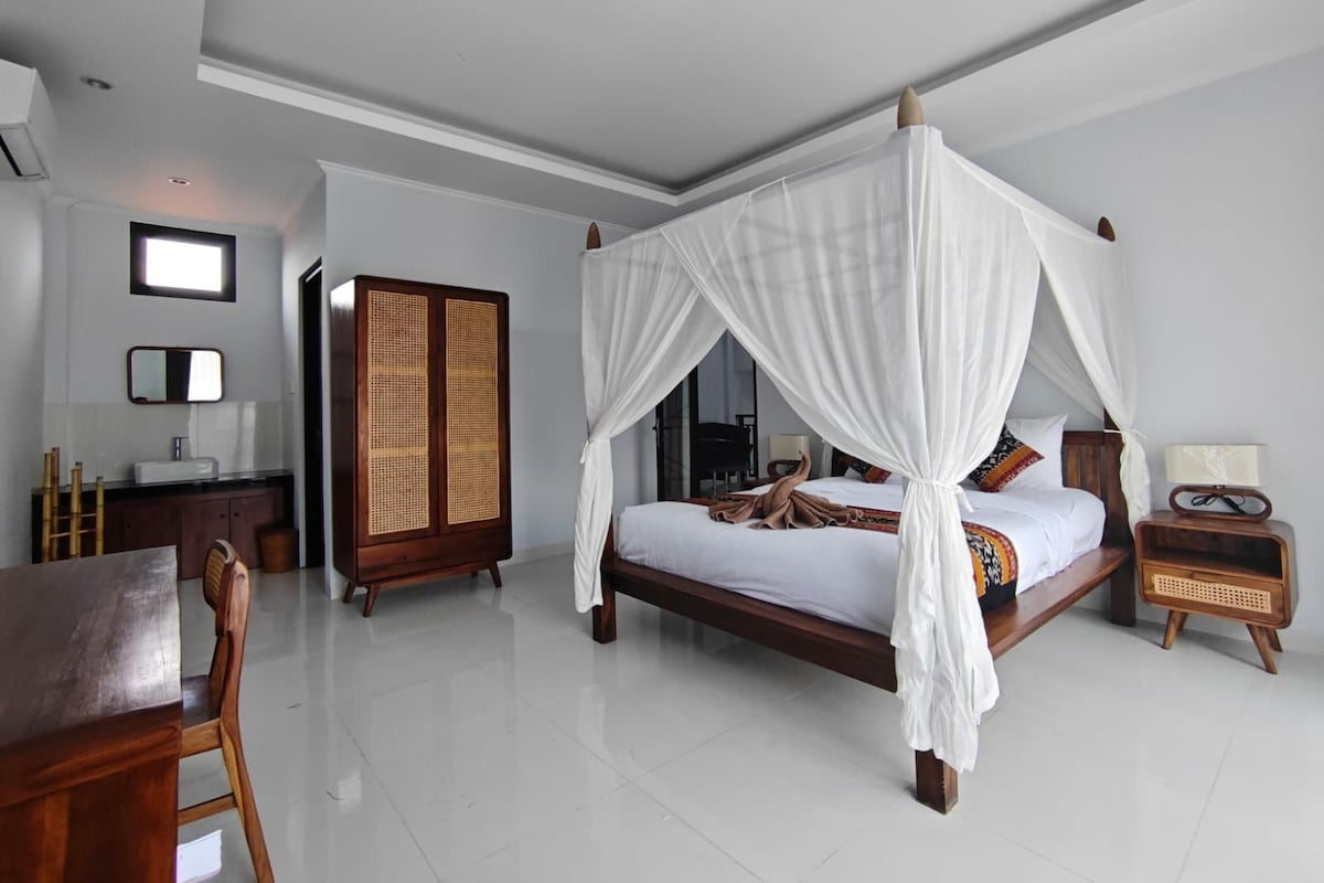 A modern bedroom with a four-poster bed, a wooden wardrobe, a desk, and a chair.