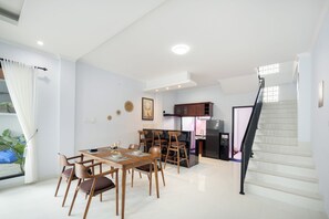 A modern kitchen with a dining area, a staircase, and a view of the outside.