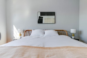 A neatly made bed with a white duvet and two pillows, flanked by bedside tables with lamps, in a room with a simple wall-mounted artwork above. - Blueground | Evanston, private entrance, nr Lakefront (Evanston)