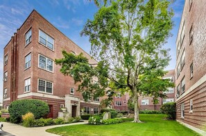 A brick building with a central courtyard, surrounded by greenery and trees. - Blueground | Evanston, private entrance, nr Lakefront (Evanston)