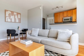 A modern living room with a sofa, a coffee table, and a dining area with chairs.