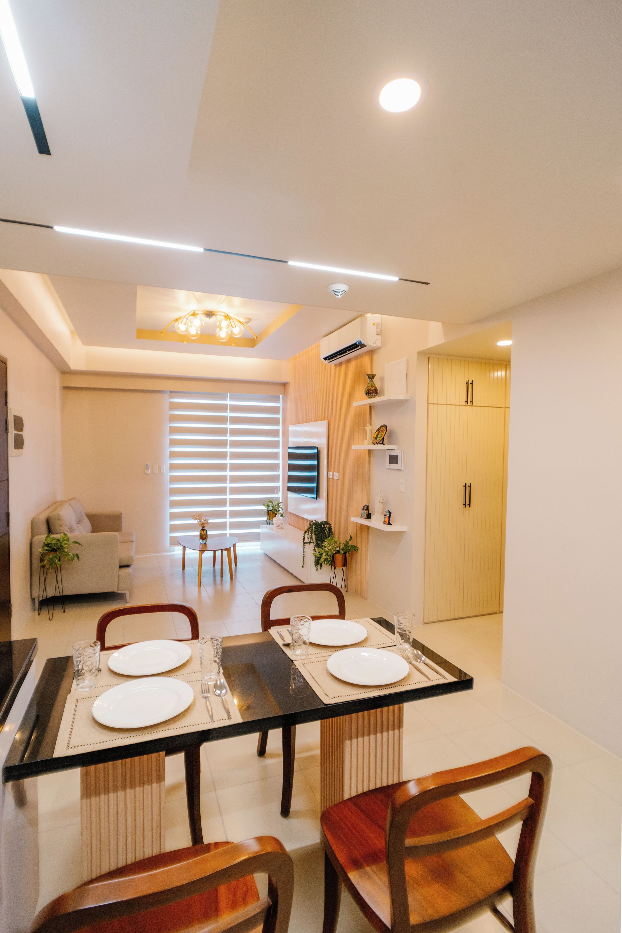 Un comedor moderno con una mesa rectangular dispuesta para cuatro personas, flanqueada por sillas de madera.