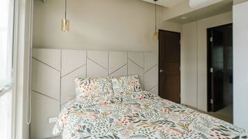 A bedroom with a bed, a window, and a door.