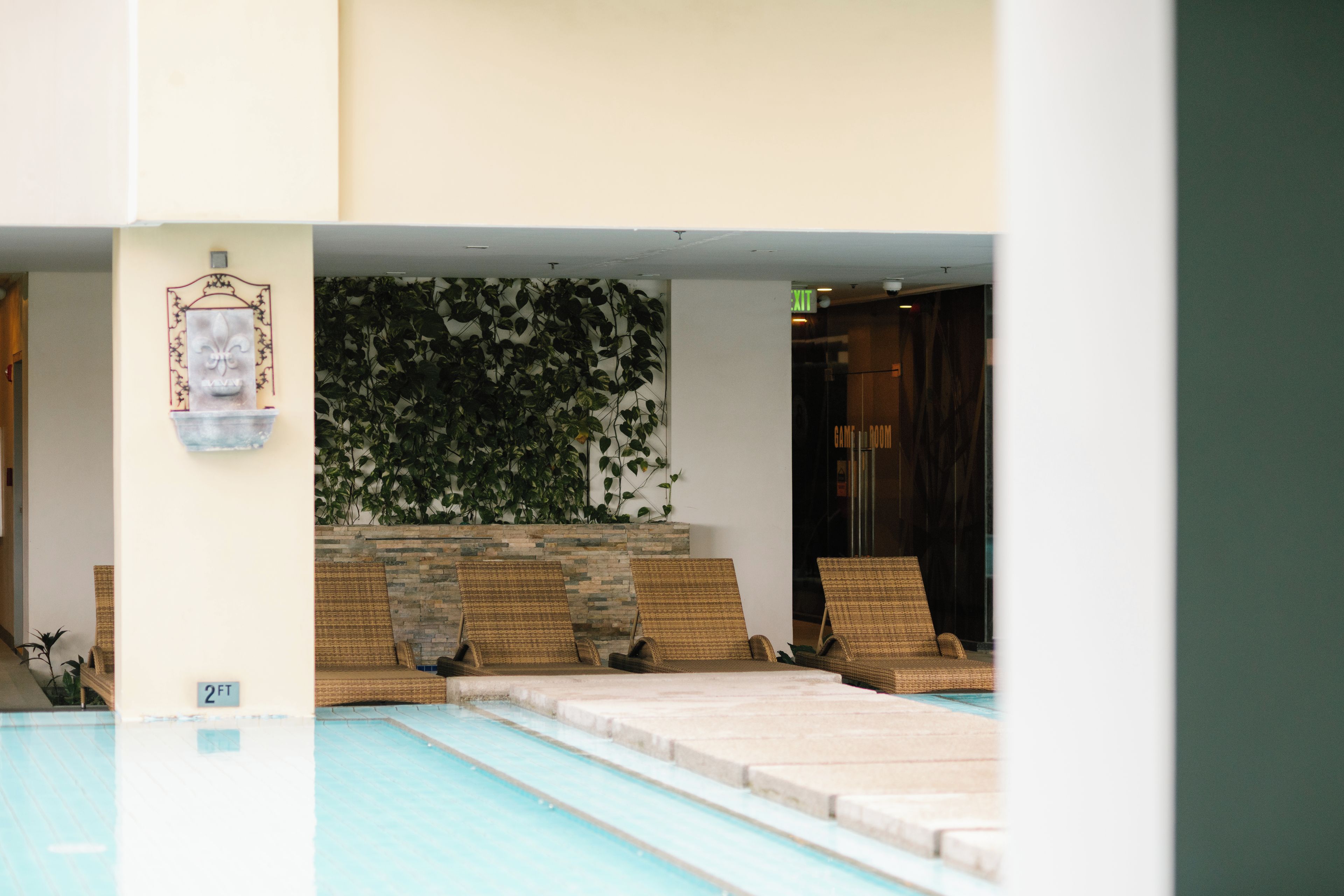 Un espace piscine agrémenté d’un mur en pierre et d’un panneau indiquant « SORTIE ».