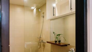 Un baño moderno con cabina de ducha de vidrio, un inodoro blanco y un lavabo con espejo superior.