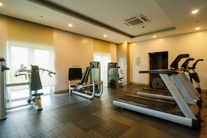 A gym with various exercise equipment including a treadmill, stationary bike, and weight machines. - Casa Honore Condominium Iloilo City (Iloilo City)