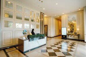 Ein Hotel-Rezeptionsbereich mit einer Marmor-Theke, einer Rezeptionistin und einem Check-in-Schalter.