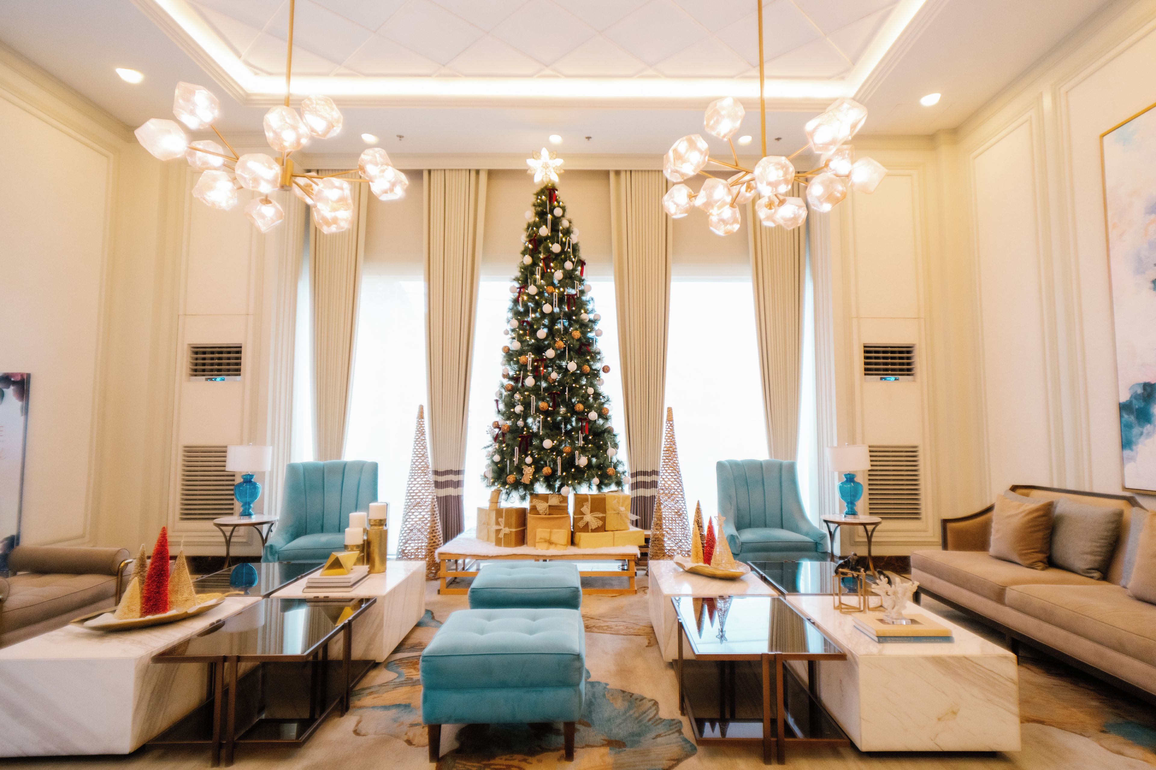 A spacious living room with a large Christmas tree, comfortable seating, and modern decor.