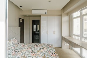 Un dormitorio con cama, armario, escritorio y ventana.