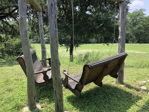 A wooden swing set with two swings in a grassy area. - Rocky River | Near Town w/ Wildlife & Large Patio (Bandera)