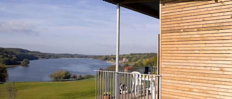 A wooden building with a balcony overlooking a lake.