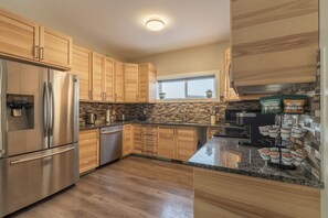Eine moderne Küche mit Holzschränken, einem Edelstahlkühlschrank, einem eingebauten Backofen und einem Fenster über der Spüle.