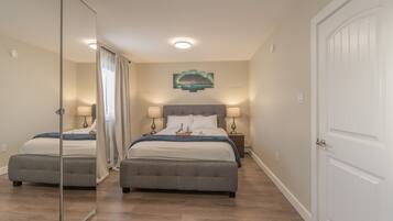 A hotel room with a double bed, two bedside tables with lamps, a mirror, and a door.