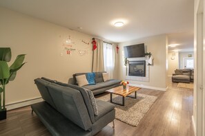 A living room with a grey sofa, a coffee table, and a fireplace. - Spacious , luxurious home for comfort, privacy and convenience. Great for Aurora (Yellowknife)