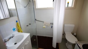 A bathroom with a white sink, toilet, and shower area. - Cherry Street Cottage (Bendalong)