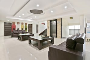 Een moderne lobby met een zithoek, een trap en een lift.