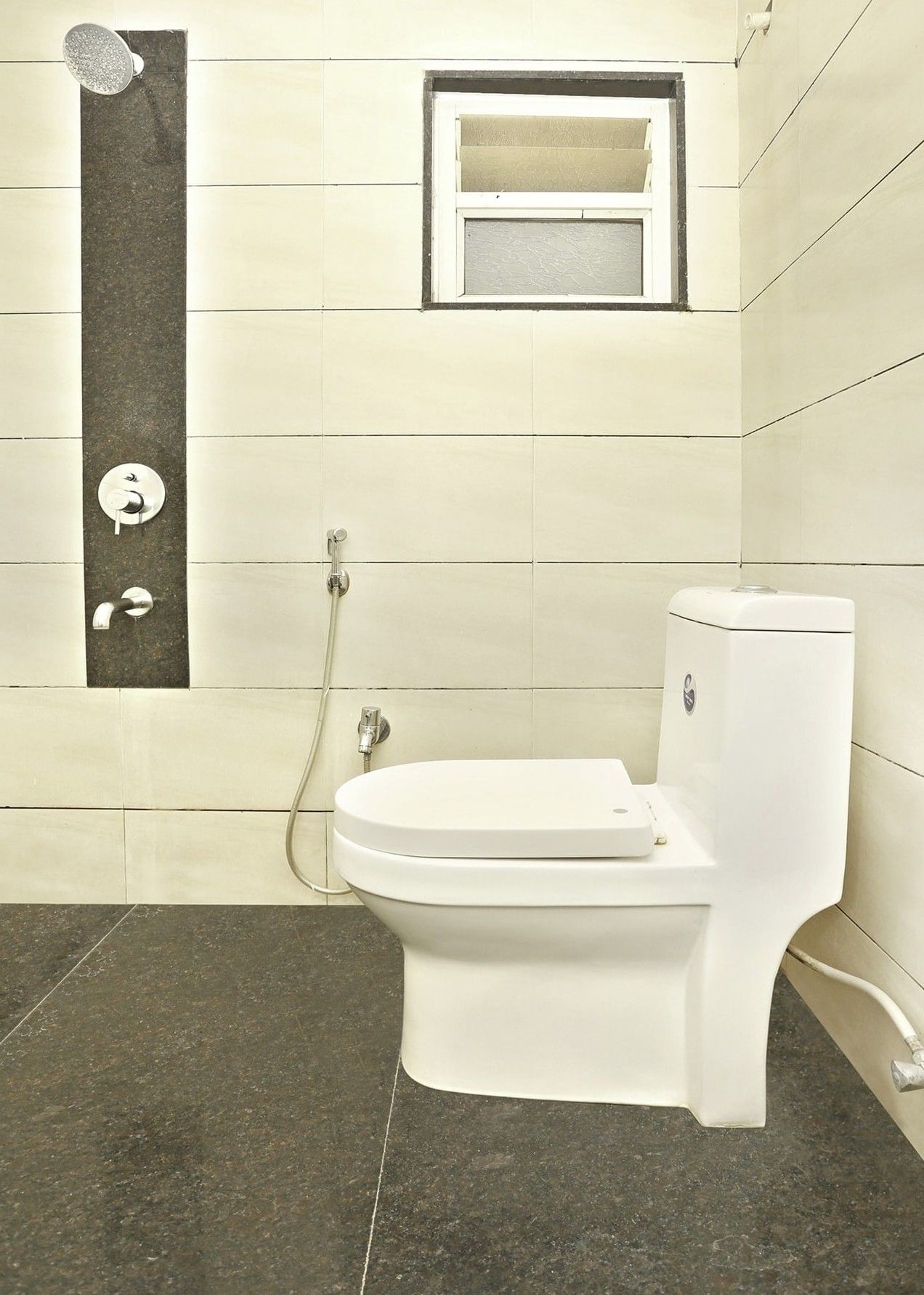 A bathroom with a toilet, a shower, and a window.