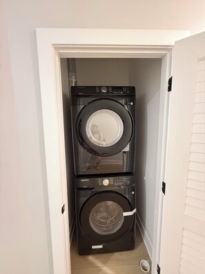Une buanderie équipée de deux machines à laver et deux sèche-linge à chargement frontal, placés l’un au-dessus de l’autre.