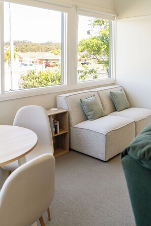 A cozy room with a built-in seating area, a small table, and a bookshelf. - Pearl Cottage – Charming Coastal Retreat (Ulladulla)
