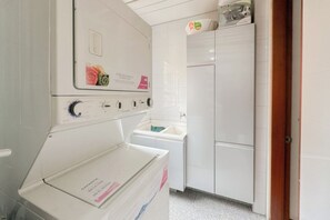 Une buanderie équipée d’un lave-linge et d’un sèche-linge à chargement frontal, d’un évier et d’un meuble de rangement.
