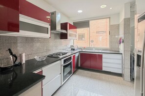 Une cuisine moderne équipée d’une cuisinière à gaz, d’un four et d’appareils électroménagers en acier inoxydable.