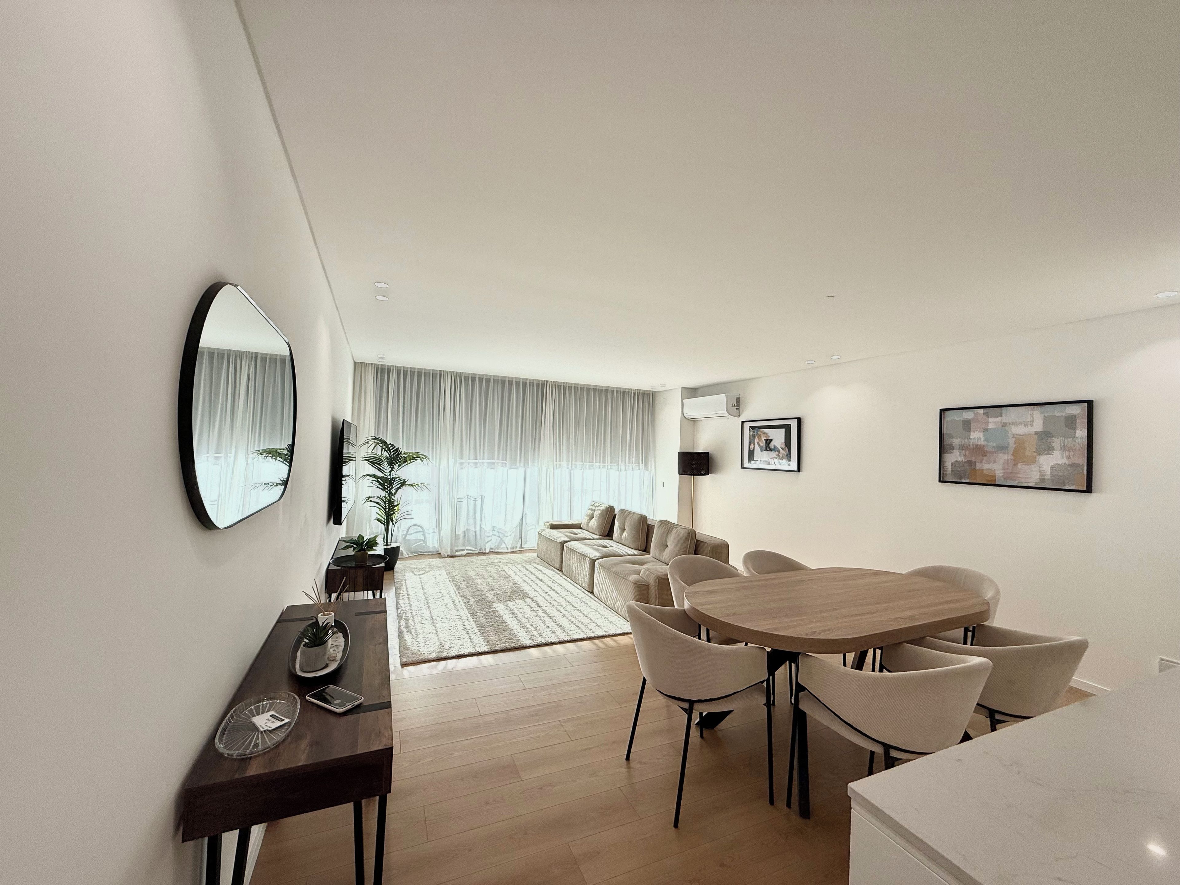Una sala moderna con comedor, un espejo grande y una planta en maceta.