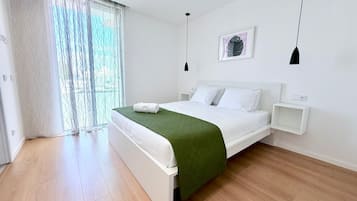 A modern bedroom with a bed, bedside tables, a window with curtains, and a wall-mounted picture.