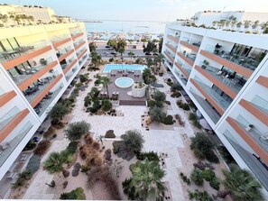 Un cortile alberghiero con piscina, zone relax e vista sul mare.