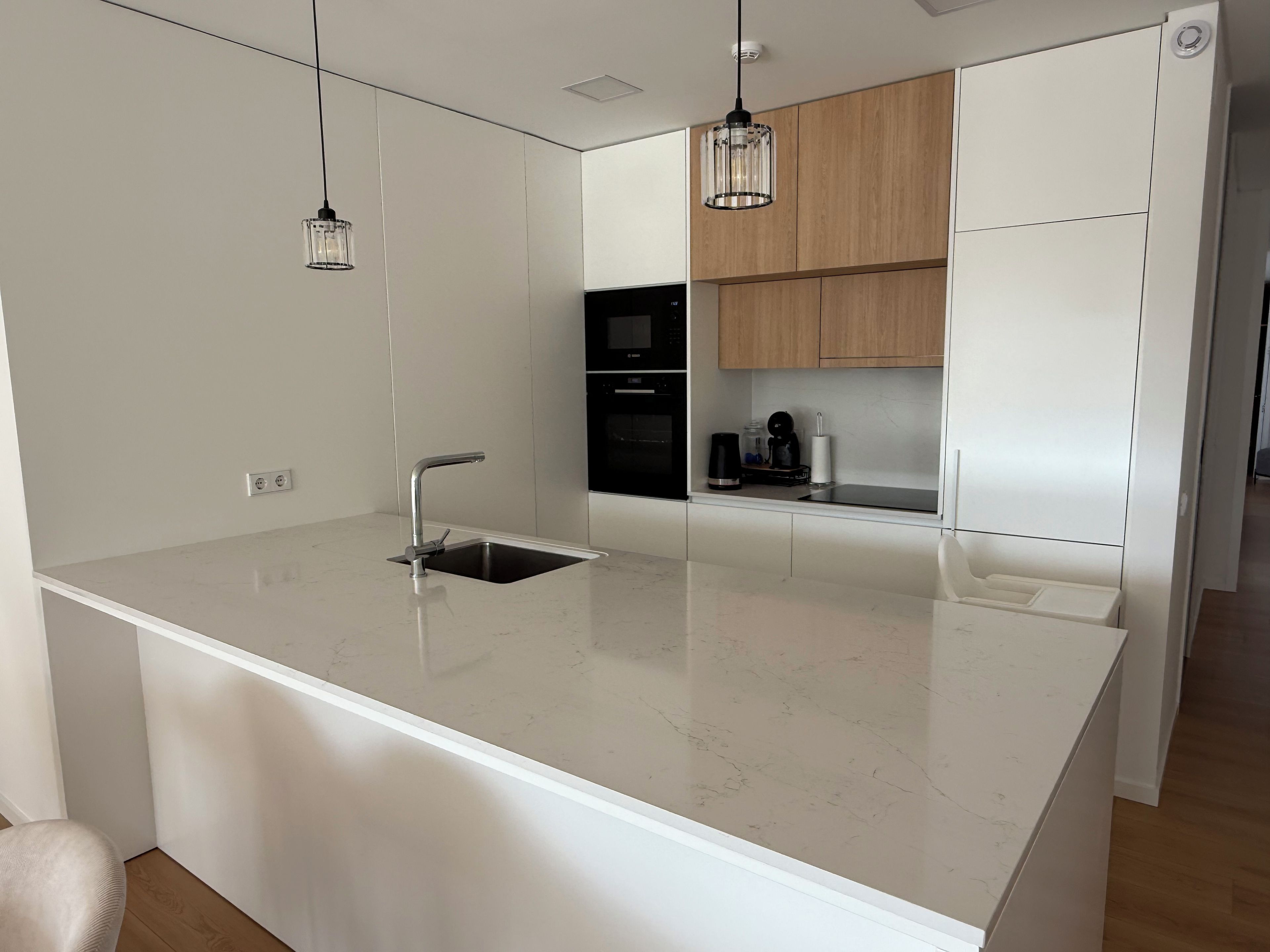 Una cocina moderna con una isla central, electrodomésticos de acero inoxidable e iluminación colgante.