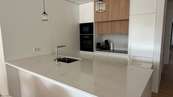 Una cocina moderna con una isla central, electrodomésticos de acero inoxidable e iluminación colgante.