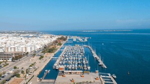 An aerial view of a marina with numerous boats docked, a clear sky, and a cityscape in the background. - Luxury family apartment with a view of the estuary (Olhão)