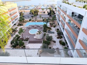 A modern hotel with a rooftop pool, surrounded by palm trees and a marina view. - Luxury family apartment with a view of the estuary (Olhão)