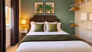 Ein Hotelzimmer mit einem Bett, einem Nachttisch, einer Lampe, einem Schrank und zwei an der Wand hängenden Bildern.