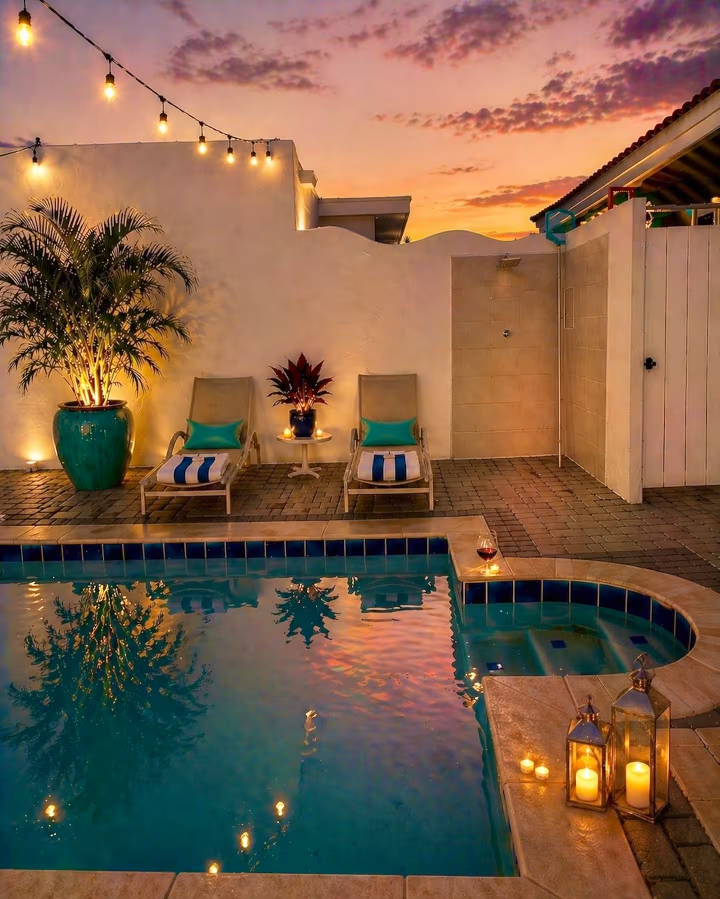 Un área de piscina con sillas de descanso, una planta en maceta y velas.