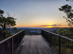 A wooden deck with metal railings overlooking a landscape during sunset. - Garden 2-Bed Villa in the Heart of Bowral (Bowral)