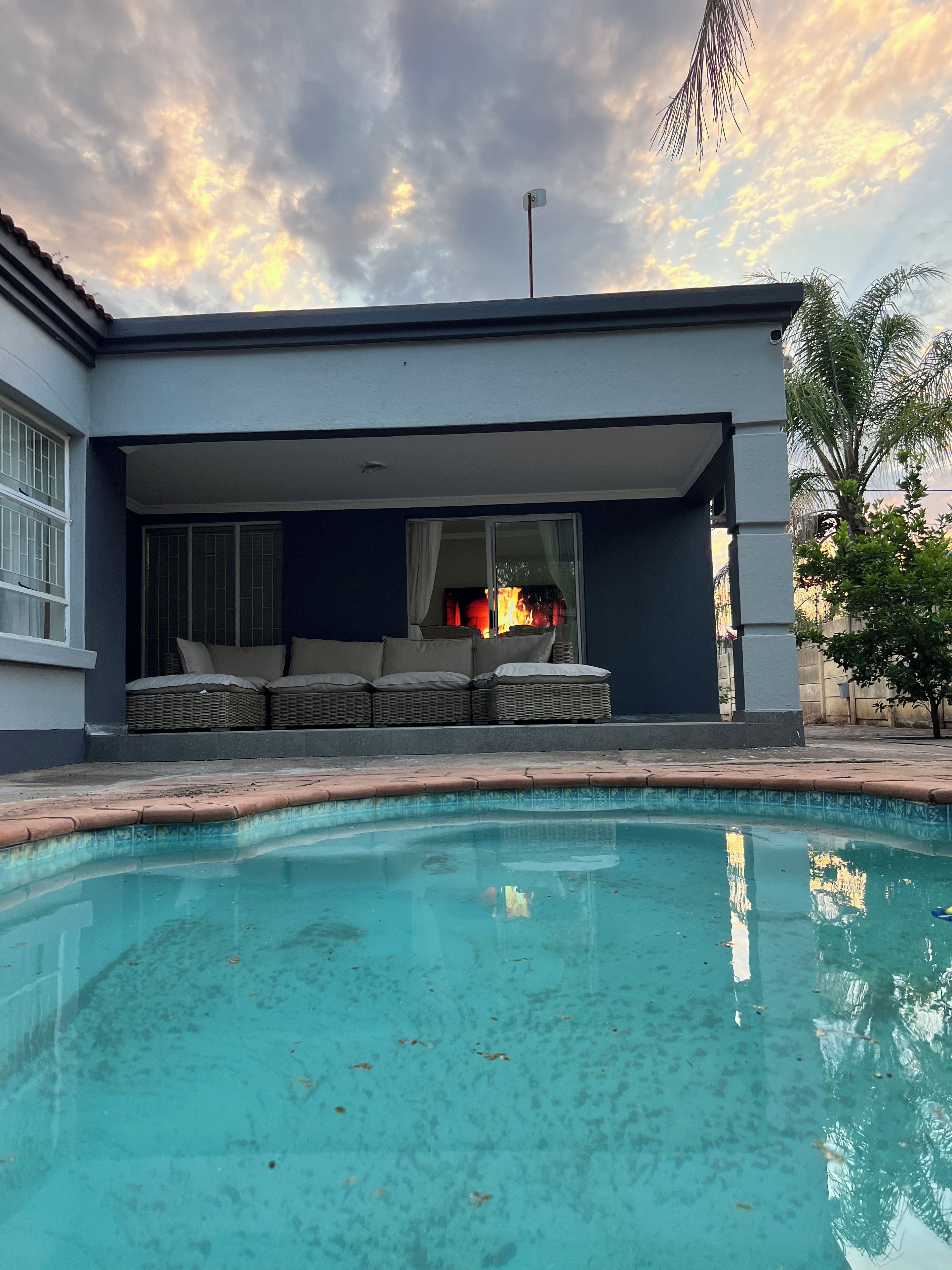 Une maison moderne dotée d’une piscine, d’un espace salon extérieur abrité et offrant une vue sur le ciel.