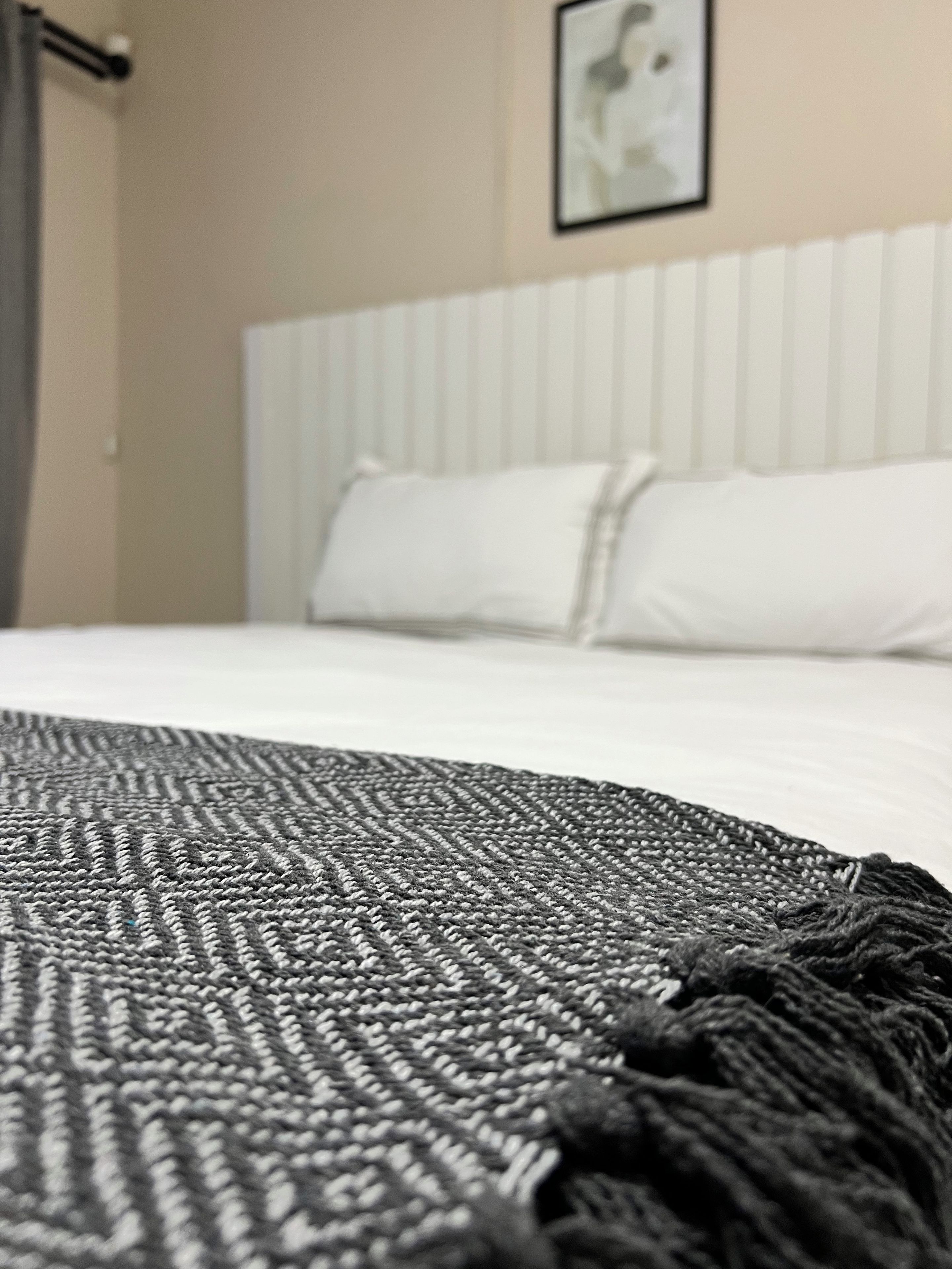 Un gros plan d’un tapis gris texturé orné d’une bordure à franges.