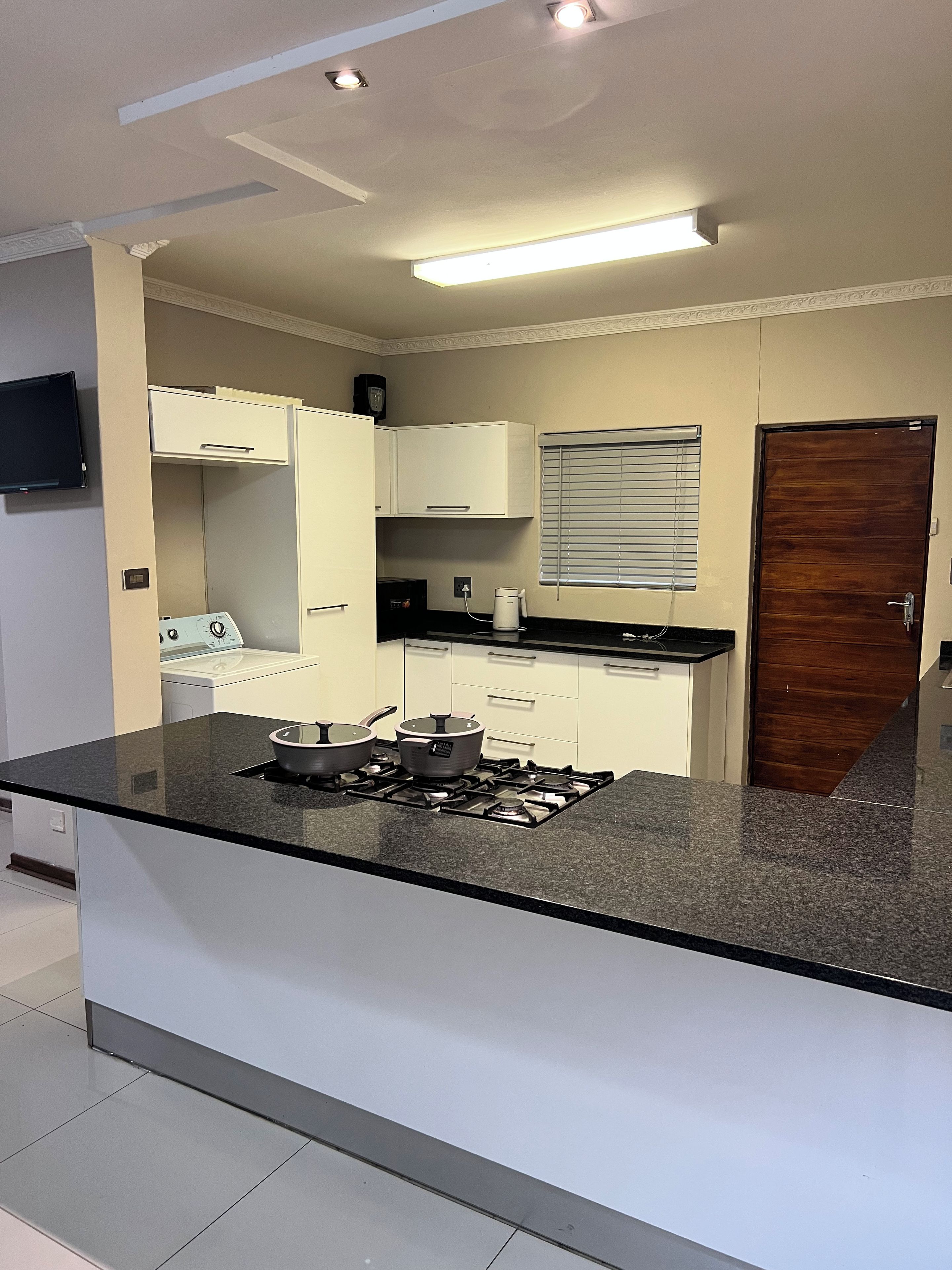 A modern kitchen with a central island, white cabinetry, and a built-in stove.