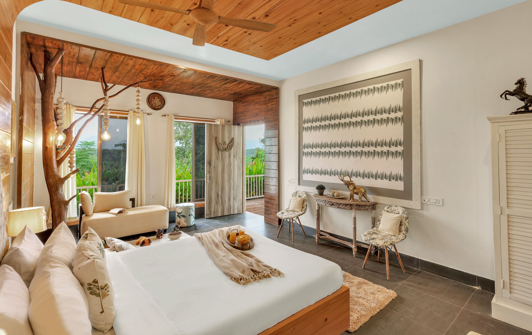 A bedroom with a large bed, a wooden ceiling, a view of greenery outside, and a framed picture on the wall.