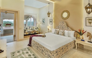 A bedroom with a large bed, a sofa, a dining table, and a view of the outdoors. - ELIVAAS Signature Junglebrooke  Cottage (Vitthalwadi)