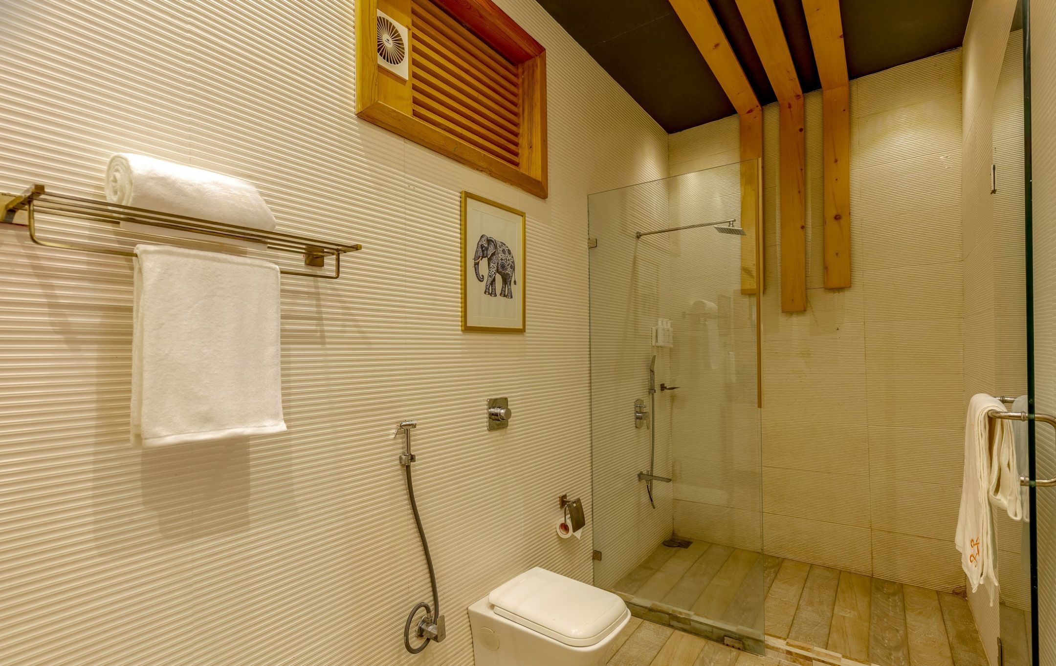 Un baño con ducha, inodoro y toallero.