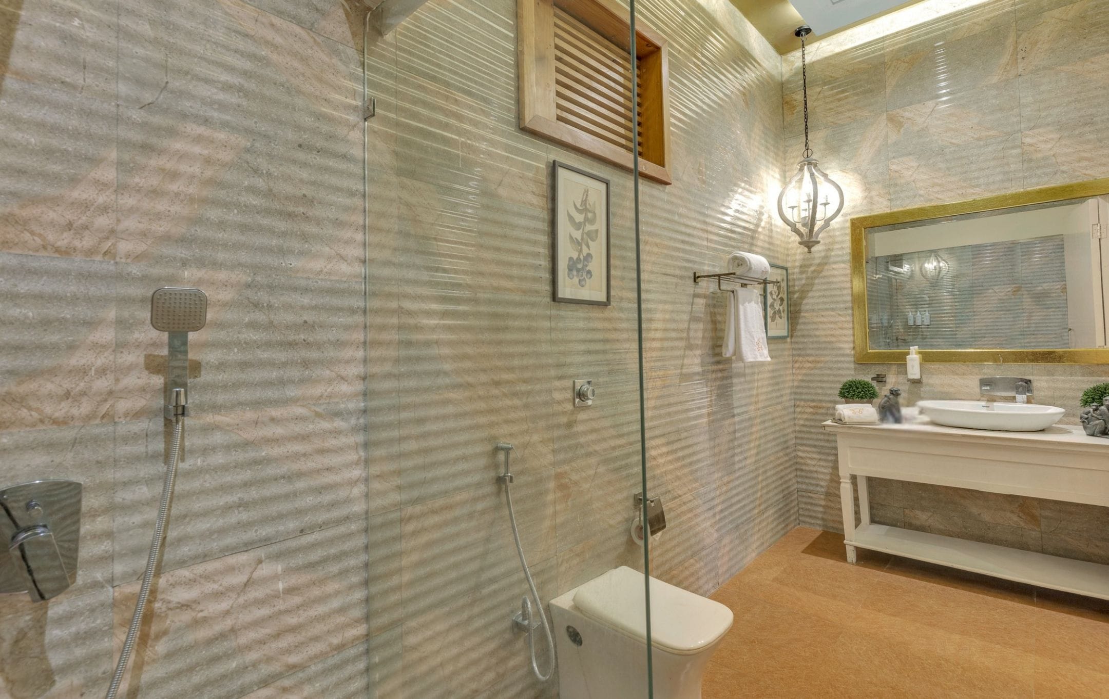 Een badkamer met een douche met glazen wand, een toilet, een wastafel met spiegel en een handdoekhouder.