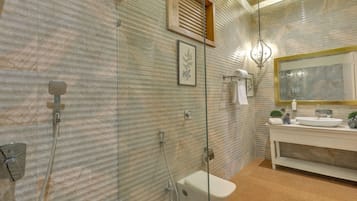 Een badkamer met een douche met glazen wand, een toilet, een wastafel met spiegel en een handdoekhouder.