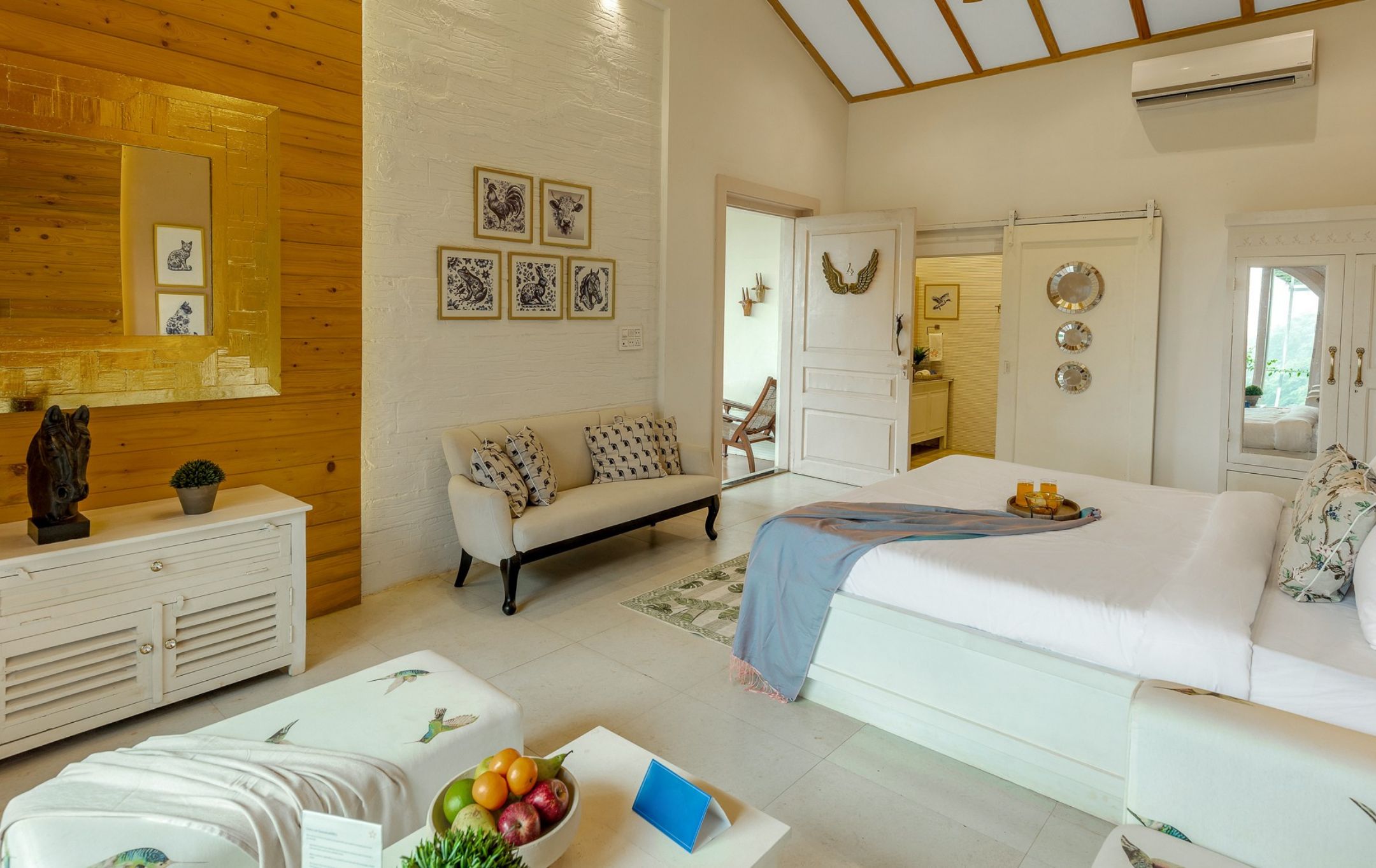 A well-lit room with a white sofa, a wooden cabinet, and a dining table with fruits and a blue napkin.