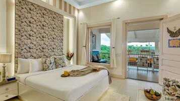 A bedroom with a bed, bedside table, and a view of a balcony.